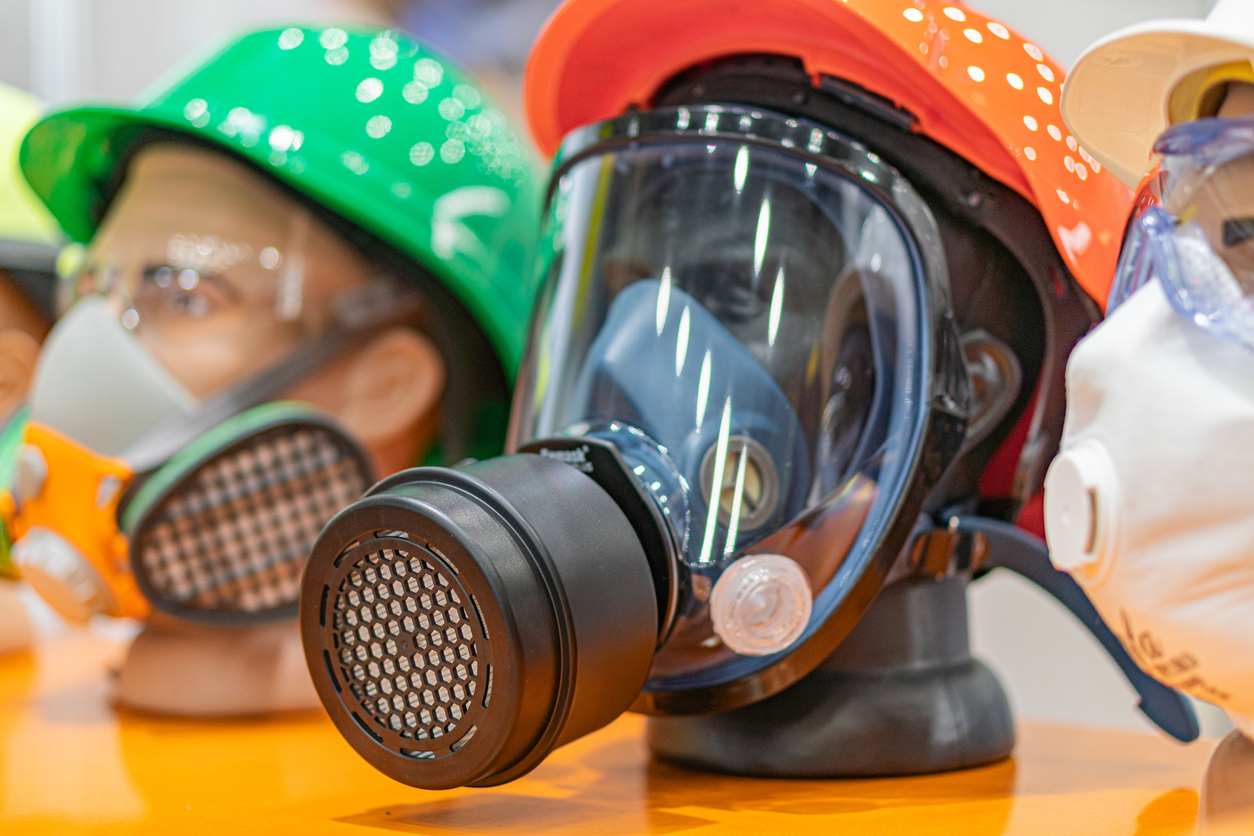 Close-up of mannequins displaying various industrial air powered respirators and helmets. Brightly colored hard hats suggest a focus on safety.